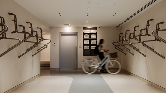 End-of-trip facilities at 50 First Avenue with bike racks in the foreground and a cyclist arriving for work in the background.