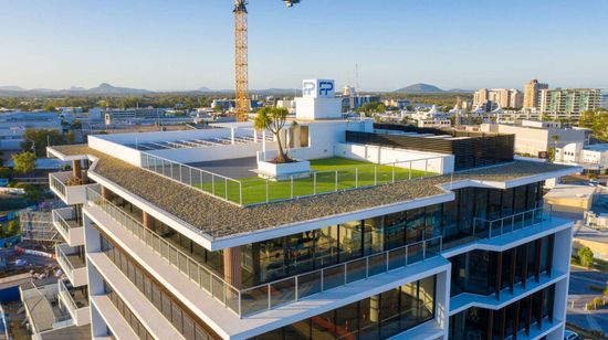 The upper floors of Foundation Place seen from above. Its rooftop consists of a green grassy field and smaller paved area.