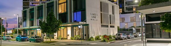 The front townhouses of Market Lane seen from across the street at dusk. Market Lane’s taller apartment buildings stand behind the townhouses.