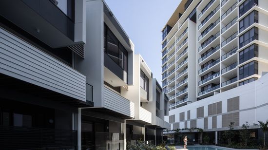 The back of Market Lane’s townhouses opening to the residents’ pool area. A large apartment building stands behind the pool.