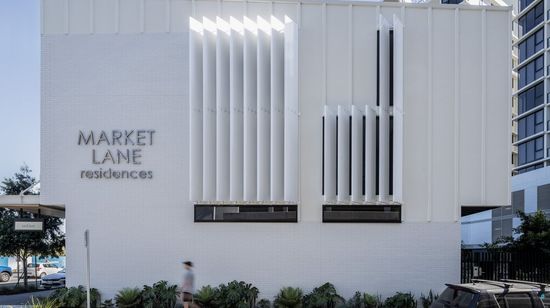 The side of the townhouses building of Market Lane, featuring a large “Market Lane Residences” sign on its white wall.