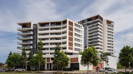 The two apartment buildings of The Corso seen from across a neighbouring grassy field. The towers are white with wooden accents.